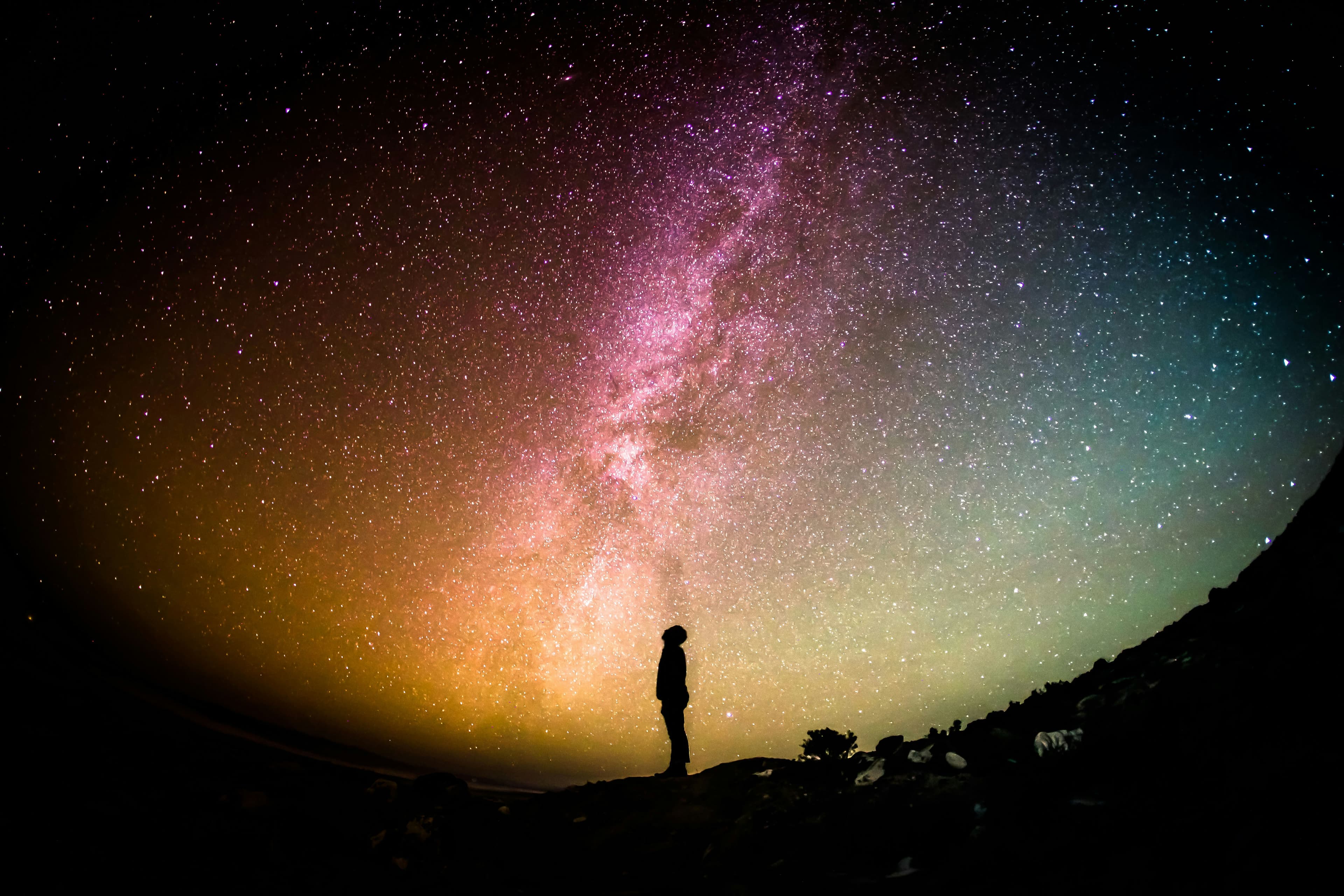 Silhouette gazing at the Milky Way stretching across the night sky