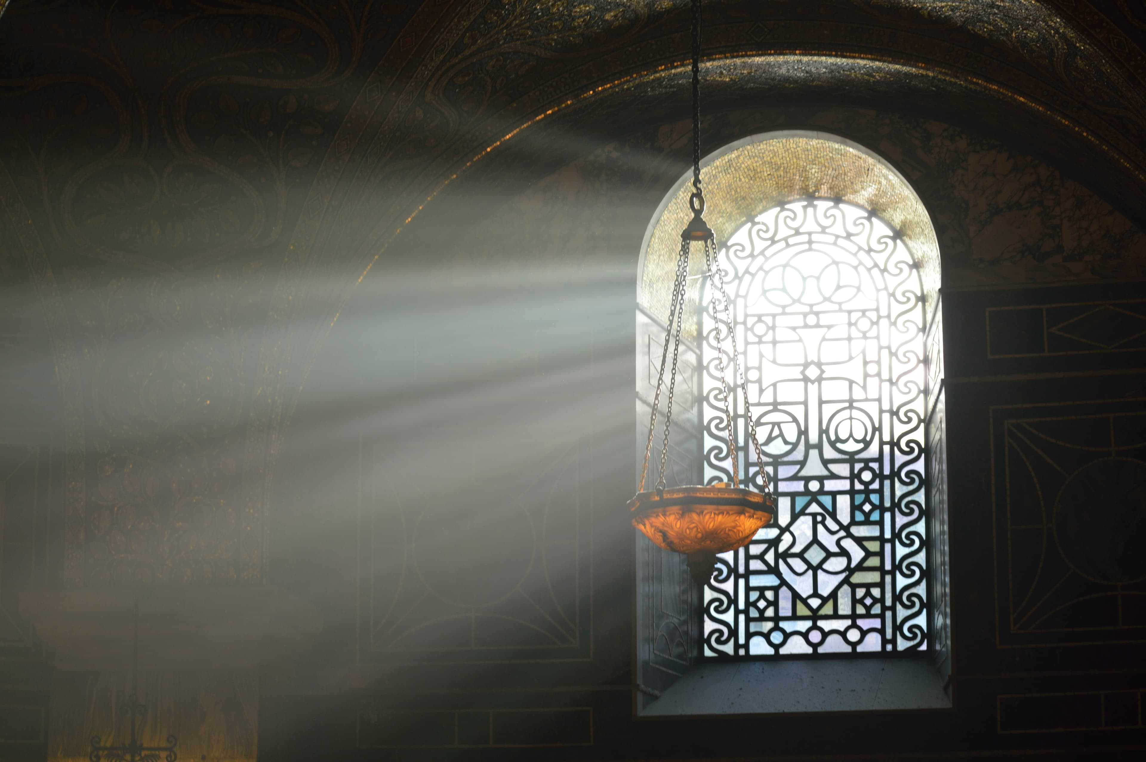 Light rays streaming through an ornate stained glass window inside a cathedral